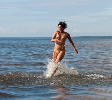 Young beautiful woman posing nude on the seaside enjoying the sea and nature