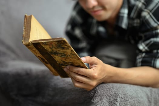 Relaxed man reading on couch spending free time on the weekend at home.