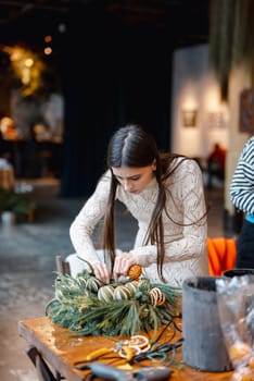 An elegant young woman passionately learning at a Christmas decor workshop. High quality photo