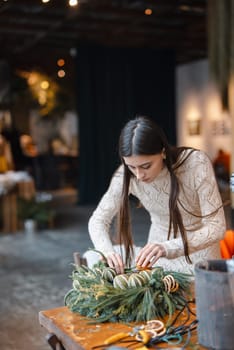 A stunning young lady deeply interested in a holiday decoration-making seminar. High quality photo