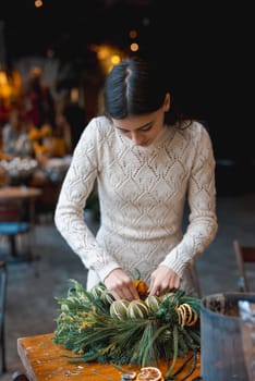 A beautiful young woman engrossed in a Christmas decor crafting workshop. High quality photo