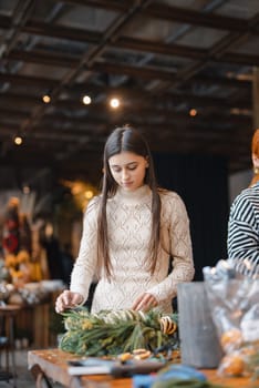 A stunning young lady deeply interested in a holiday decoration-making seminar. High quality photo