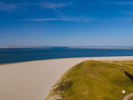 A captivating aerial view of Texel, Netherlands, showcasing a tranquil beach with rolling waves and the vast, blue ocean stretching to the horizon.