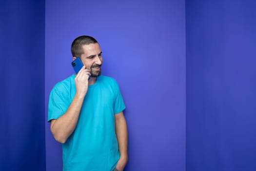 Happy young man talking with mobile phone on color background. High quality photo
