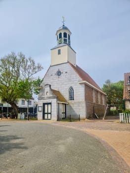 A majestic church with a clock tower stands tall and proud in the heart of Texel, surrounded by the bustling activity of the town. De Koog Texel