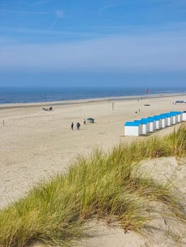A tranquil beach setting with golden sand and charming huts nestled along the coast of Texel, Netherlands.