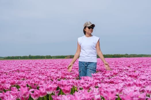 A woman elegantly stands amidst a vibrant sea of pink tulips in a field in Texel, Netherlands.