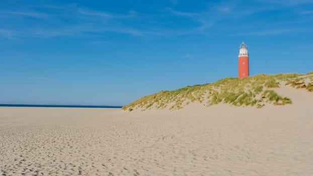 A majestic lighthouse perched on top of a sandy dune, overlooking the endless horizon of the Texel Netherlands.