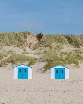 Colorful beach huts line the sandy shore of Texel, Netherlands, basking in the warm sunlight.
