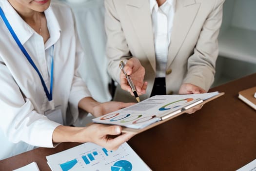 Collaborative business woman meeting hands analyzing financial charts and graphs on office desk for strategic planning.