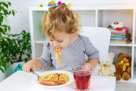 The child eats spaghetti lunch. Selective focus. Food.
