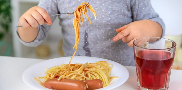 The child eats spaghetti lunch. Selective focus. Food.