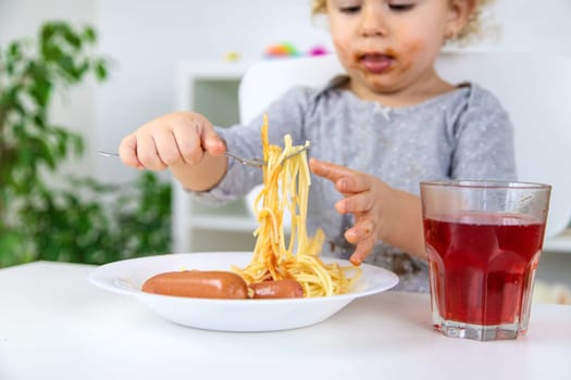 The child eats spaghetti lunch. Selective focus. Food.