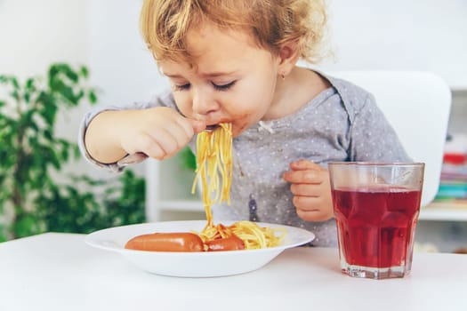 The child eats spaghetti lunch. Selective focus. Food.