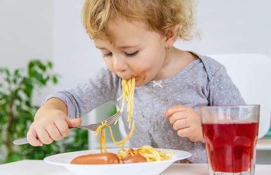 The child eats spaghetti lunch. Selective focus. Food.