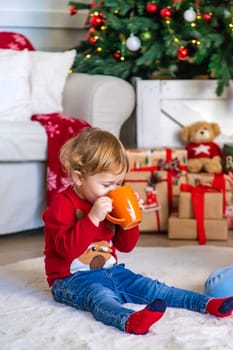 Children drink tea near the Christmas tree. Selective focus. Kid.