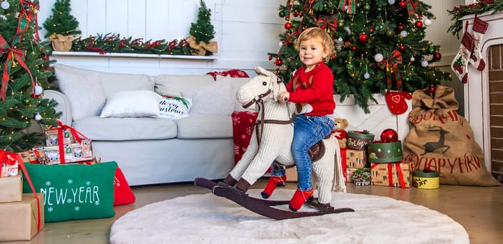 Child on horseback near the Christmas tree. Selective focus. Kid.