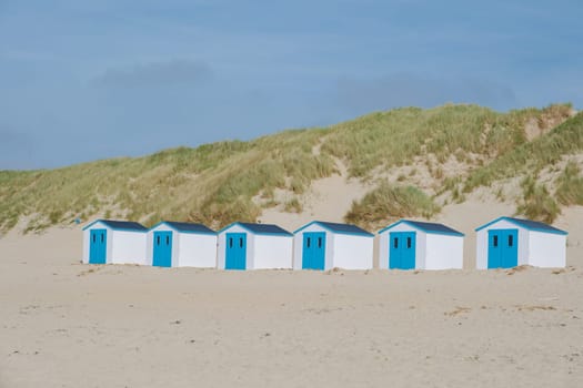 A colorful row of beach huts stands proudly on the sandy shores of Texel, Netherlands, under a clear blue sky. De Koog beach Texel