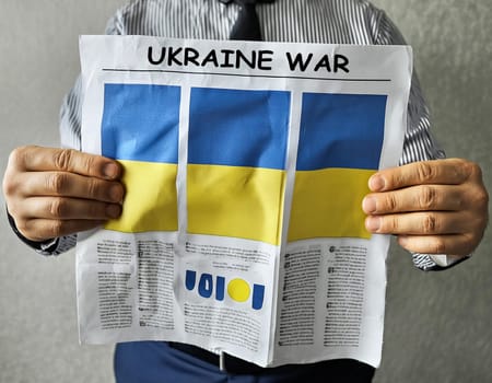 Hand holding a newspaper with the drawing of the flag of Ukraine on a white background