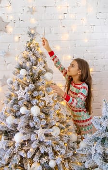 A child hangs a star on a Christmas tree. Selective focus. Kid.