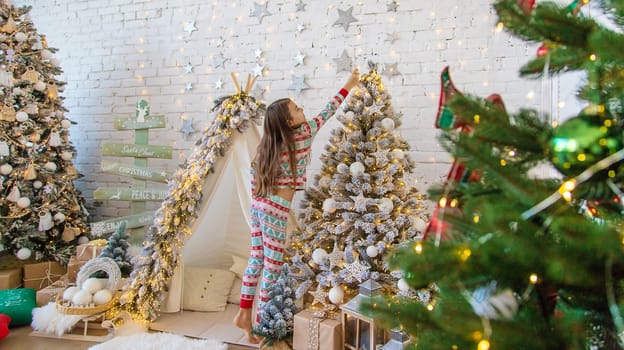 A child hangs a star on a Christmas tree. Selective focus. Kid.