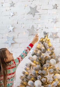 A child hangs a star on a Christmas tree. Selective focus. Kid.