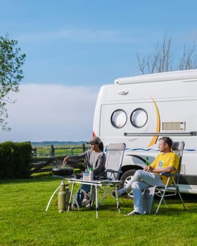 Two individuals are seated in front of their RV, enjoying the peaceful surroundings of a grassy field in Texel, Netherlands. camping at a farm in Texel Netherlands
