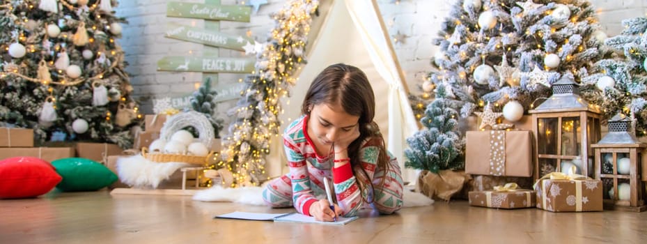 Children write a letter to Santa under the tree. Selective focus. Kid.