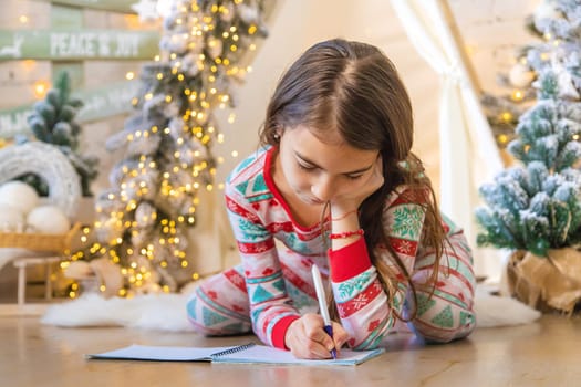 Children write a letter to Santa under the tree. Selective focus. Kid.