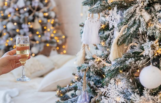 woman with champagne in her hands near the Christmas tree. Selective focus. Holiday.