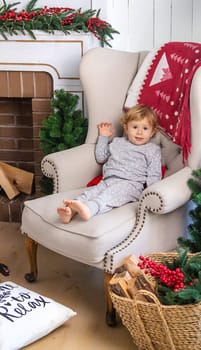 A child in a chair near the Christmas tree. Selective focus. Baby.