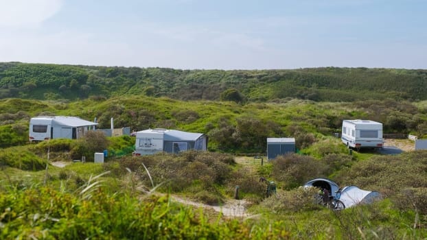 A cluster of modern RVs parked in harmony on a lush green hillside in Texel, Netherlands.