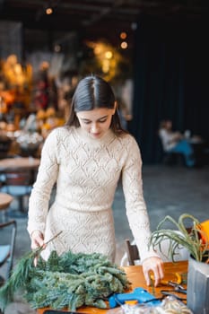 A young lady creating a Christmas wreath at a holiday decor class. High quality photo