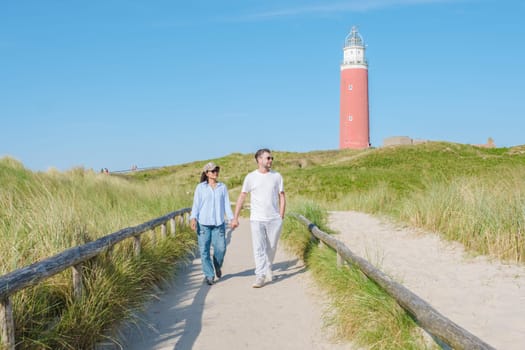 A couple leisurely walking along a scenic path near the Texel Lighthouse, enjoying the stunning coastal views and the sound of crashing waves.
