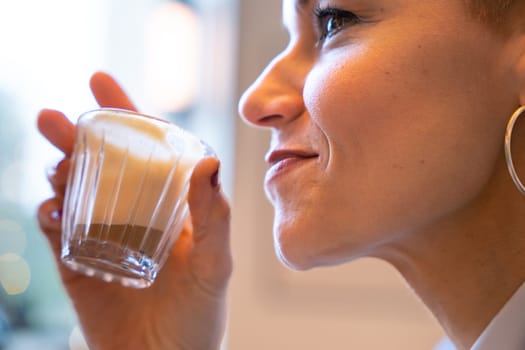 Side view Businesswoman in a trendy cafe drinking coffee. Beautiful Caucasian Model Reflections of the windows.