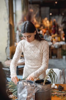 A beautiful young woman engrossed in a Christmas decor crafting workshop. High quality photo