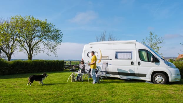 A man and his faithful dog stand next to an RV in a picturesque grassy field in Texel Netherlands, soaking in the serenity of their surroundings. a couple at a camping farm