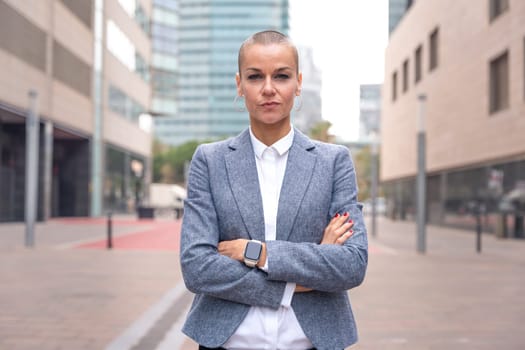 Close-up of a caucasian businesswoman looking seriously at the camera in a suit standing in outdoor workspace. Front view of a young lawyer with thoughtful expression staring