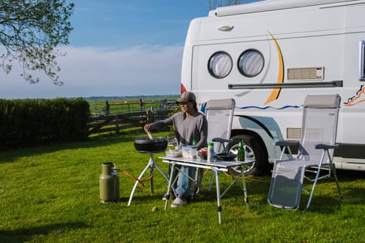 A woman sits quietly at a table, with an RV in the background. The scene exudes a sense of peace and anticipation for the journey ahead. camping at a farm in Texel Netherlands