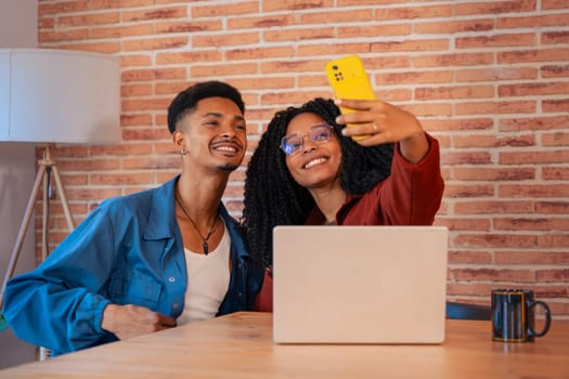 Multiethnic couple using a smartphone makes each other smile at home, a Latino boyfriend and an African-American girlfriend on social media try a new mobile app