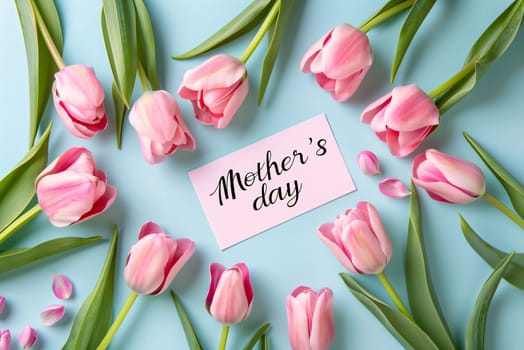 Mother's Day: Pink tulips and card with text Happy Women's Day on blue background