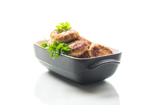 fried meat cutlets in a ceramic form on a wooden table .