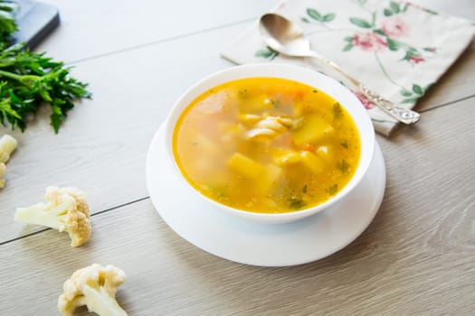 Homemade chicken vegetable soup on rustic wooden background .