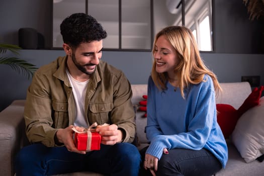 Portrait of happy and smiling young man and woman hugging and holding red gift box.