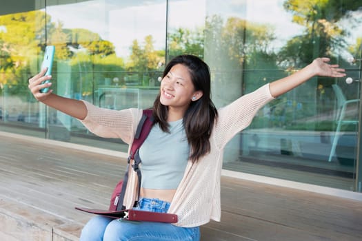 Happy young chinese woman taking a selfie with smartphone