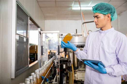 At the beverage bottling factory a quality control officer uses a tablet to ensure line accuracy. Machinery engineer inspects and maintains machines for proper basil or chia seed bottling.