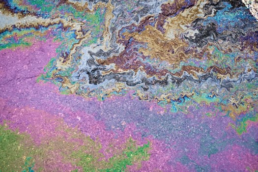 Colorful texture of spilled petrol oil on wet pavement.