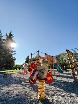 Little girl swings on a spring-swing with her hair blowing in the wind. High quality photo