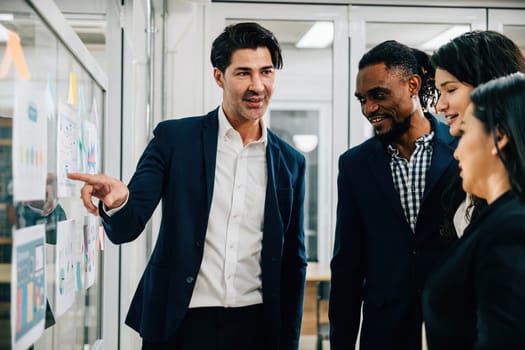 A team of professionals gathers in a boardroom meeting, brainstorming and planning on a glass wall. Their collaboration and creative thinking are vital to the success of their business startup.