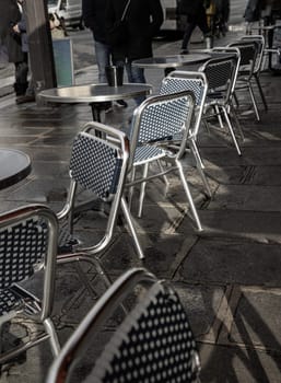 France, Paris - Jan 03, 2024 - Stainless steel chairs and tables outside a cafe on street in Paris city. Empty outdoor cafe seating area with Metal chairs and tables, Copy space, Selective focus.